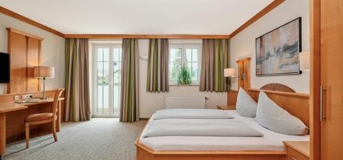 a hotel room with two beds and a desk at Hotel Königgut in Wals