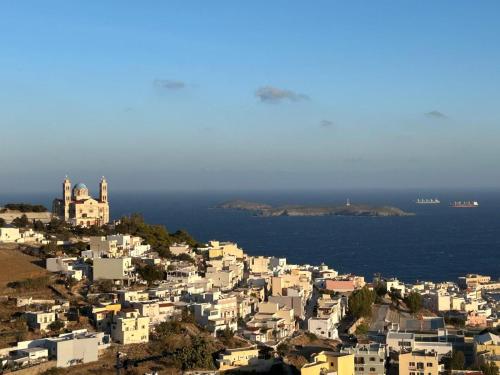 a group of white buildings on a hill next to the ocean at Delfini Suites in Ano Syros