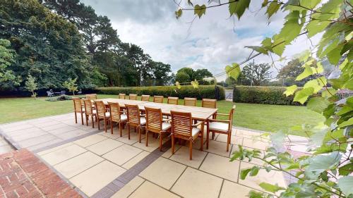 a long wooden table and chairs in a garden at Hedgerows House New Forest in Ringwood