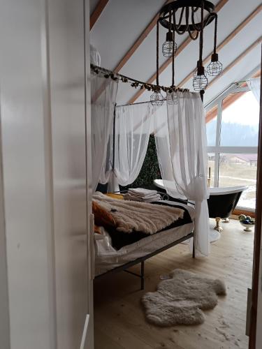 a bedroom with a bed with a canopy and a tub at Farm Stay Agroturism Bori Punct Gastronomic Local in Gura Humorului