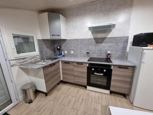 une petite cuisine avec un évier et une cuisinière dans l'établissement Studio en plein cœur du bassin d'Arcachon, à Audenge