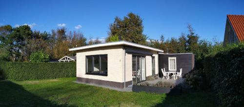 a small white house with two chairs in a yard at Villa dichtbij het strand in Ouddorp
