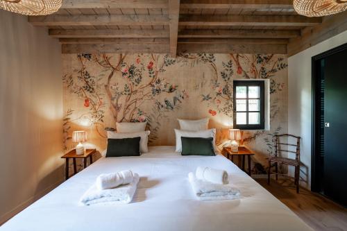 une chambre avec un grand lit blanc avec un papier peint fleuri dans l'établissement Maison Marie-Lys, à Uza