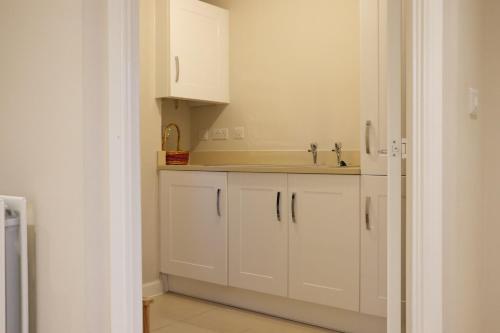 a kitchen with white cabinets and a sink at Bicester Villa - 6 Bed - Sleeps 14 in Bicester