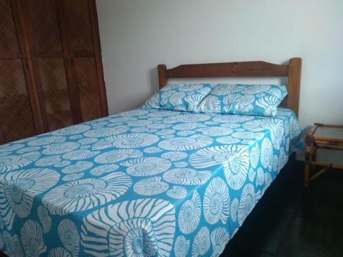 a bedroom with a bed with a blue and white bedspread at Apartamento em Ubatuba Arejado Próximo a Praia in Ubatuba
