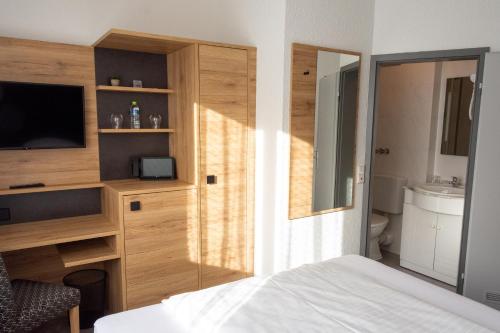 a bedroom with a bed and a tv and a bathroom at Hotel-Cocco-Bello in der Villa Foret in Ludwigsburg