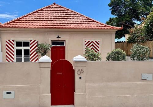 a house with a red door and a fence at THE BOAT HOUSE Sea Front and Private Pool in Funchal