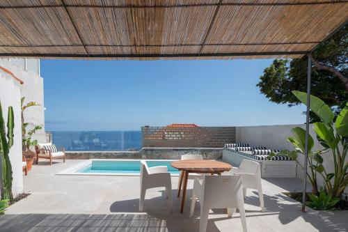 a patio with a table and chairs and a pool at THE BOAT HOUSE Sea Front and Private Pool in Funchal
