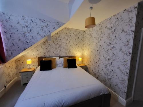 a bedroom with a white bed with floral wallpaper at St George's Guest House in York