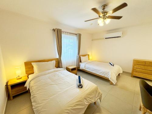 a bedroom with two beds and a ceiling fan at Bon Bini Suites in Oranjestad