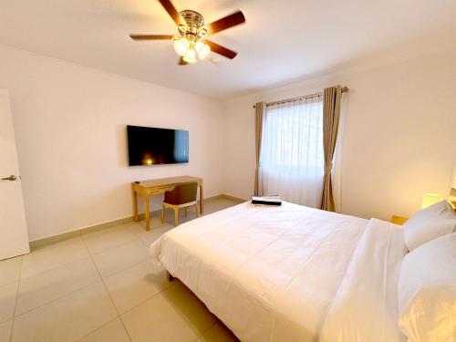 a bedroom with a bed and a table and a ceiling fan at Bon Bini Suites in Oranjestad