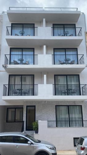 an apartment building with balconies and a car parked in front at Swieqi Malaika New Apt 2 with COURTYARD in Is-Swieqi