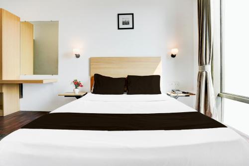 a large white bed in a room with a window at Super Townhouse PBG Mall Vashi in Turambhe