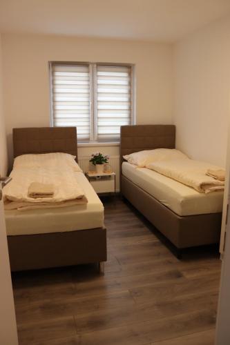 two beds in a room with two windows at Apartmán Nerudova Terasa in Polná