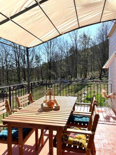 a wooden table and chairs under a patio umbrella at Bungalow à la campagne in Riventosa
