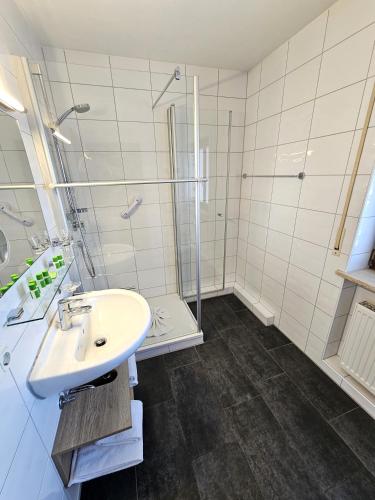 a white bathroom with a sink and a shower at Hotel Cafe Fuggerhof in Oberstdorf