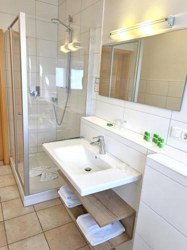 a white bathroom with a sink and a shower at Hotel Cafe Fuggerhof in Oberstdorf