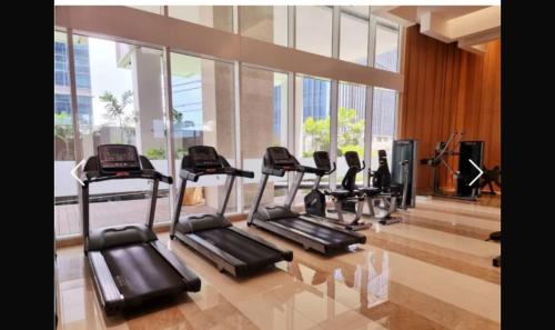 a gym with several tread machines in a room with windows at Podomoro Apartment 2BR FullFacility Liberty in Medan