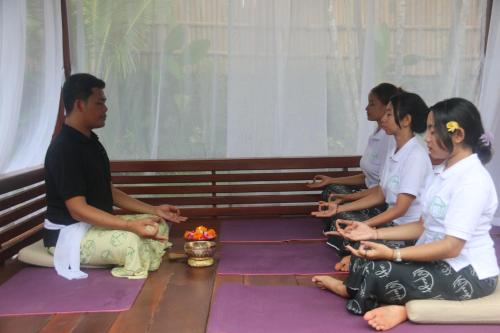 a group of people sitting on a bench in meditation at The Manja Retreat Lovina in Buleleng