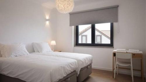 a bedroom with a bed and a desk and a window at Maçãs Home-Land Sea View at The Beach in Colares