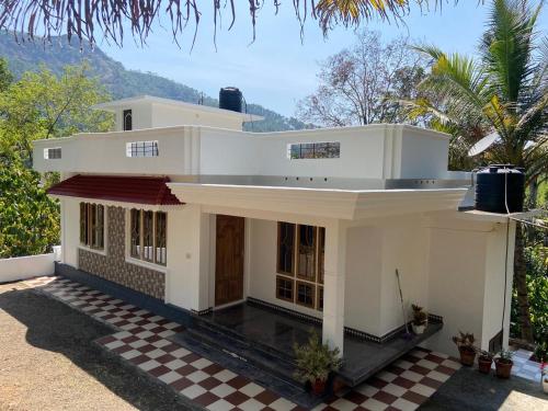 a white house with a checkered floor at The Lovely Home Stay in Munnar