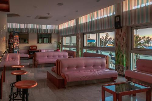 a waiting room with pink leather couches and tables at Hotel Centrale Miramare in Rimini