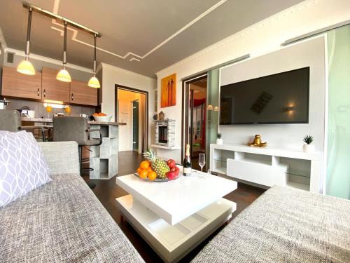 a living room with a television and a table with fruit on it at RelaxApartments ABENDSONNE im Herzen des Harzes - ein El Dorado für Wanderer, Biker und Ruhesuchende - mit sonnigem Balkon und Platz für bis zu 3 Personen in Hahnenklee-Bockswiese