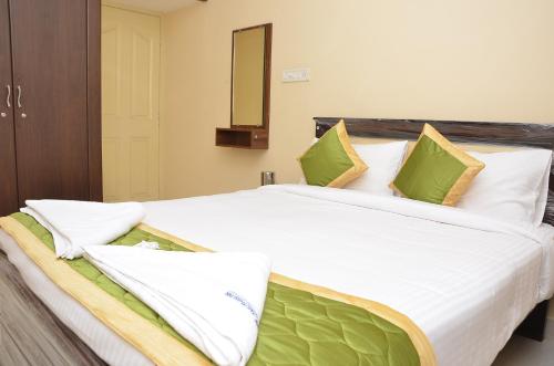 a bedroom with a large white bed with green pillows at Amutham Inn in Chennai