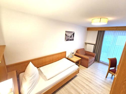 a small room with a bed and a chair at Hotel Cafe Fuggerhof in Oberstdorf