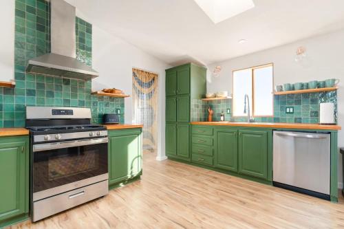 a green kitchen with wooden floors and green cabinets at Secluded-jt-spa-pool-firepit-sauna-game Room! in Yucca Valley