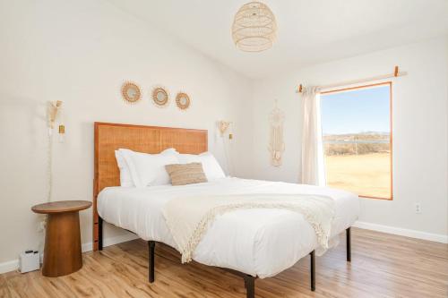 a white bedroom with a large bed and a window at Secluded-jt-spa-pool-firepit-sauna-game Room! in Yucca Valley