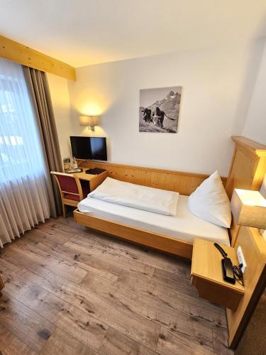 a hotel room with a bed and a desk at Hotel Cafe Fuggerhof in Oberstdorf