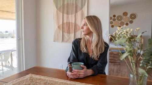 a woman sitting at a table holding a cup at Secluded-jt-spa-pool-firepit-sauna-game Room! in Yucca Valley