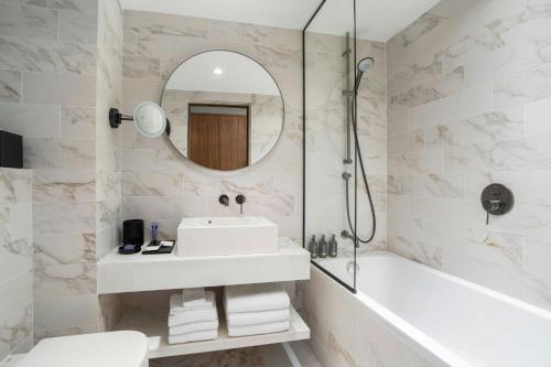 a bathroom with a sink and a tub and a mirror at Cardo Roma, Autograph Collection in Rome