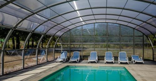 une serre avec des chaises et une piscine dans l'établissement Brit Hotel Confort Nancy Lunéville, à Lunéville