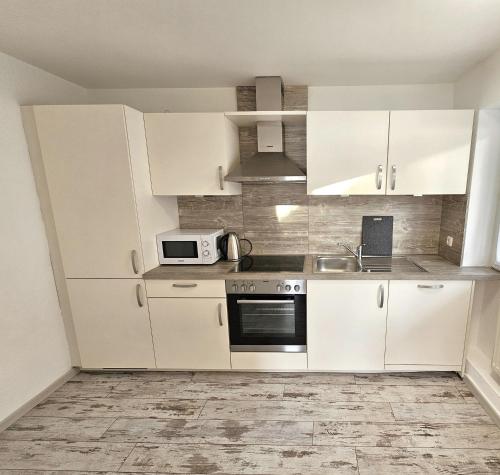 a kitchen with white cabinets and a microwave at Hotel Cafe Fuggerhof in Oberstdorf