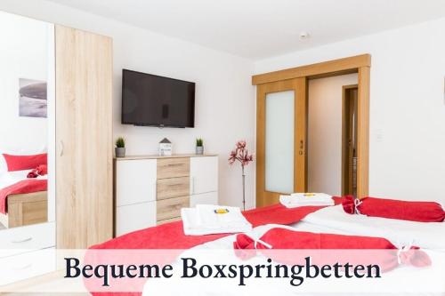 two beds in a bedroom with a television on a wall at Ferienwohnung EDEN Apartment´s Vinum in Friedrichshafen