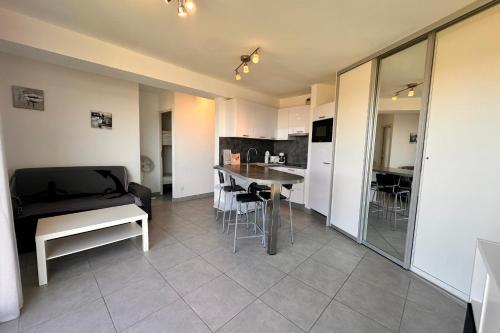 Il comprend un salon et une cuisine avec une table et des chaises. dans l'établissement Les pieds dans le sable Appartement Vue Mer 1 chambre 1 cabine, au Grau-du-Roi