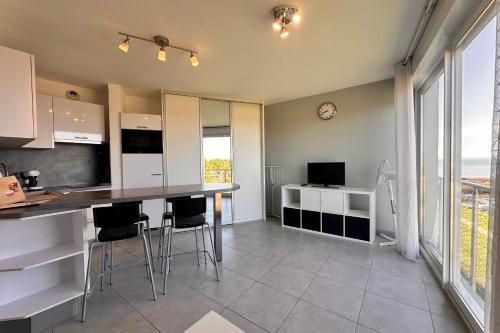 - une cuisine avec un comptoir et des chaises dans la chambre dans l'établissement Les pieds dans le sable Appartement Vue Mer 1 chambre 1 cabine, au Grau-du-Roi