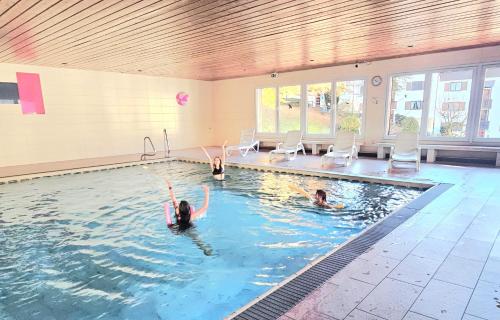 un groupe de personnes nageant dans une piscine dans l'établissement Alp-Juwel - mit Hallenbad und Sauna - direkt an der Skipiste, à Missen-Wilhams