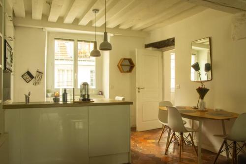 - une cuisine avec une table, une table et des chaises dans l'établissement Loft parisien au coeur du marais, à Paris
