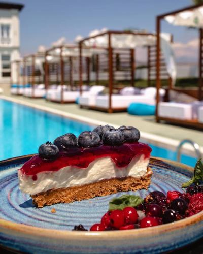 a piece of cake with berries on a plate next to a pool at Kompleksi Exalco-Al in Shkodër