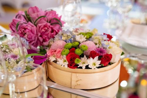 a wooden bucket filled with flowers on a table at InterContinental Hanoi Landmark72 by IHG in Hanoi