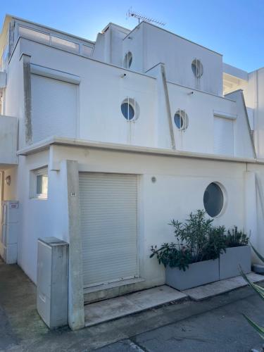 a white house with a garage at MARINA Belle vue avec appontement in Le Grau-du-Roi