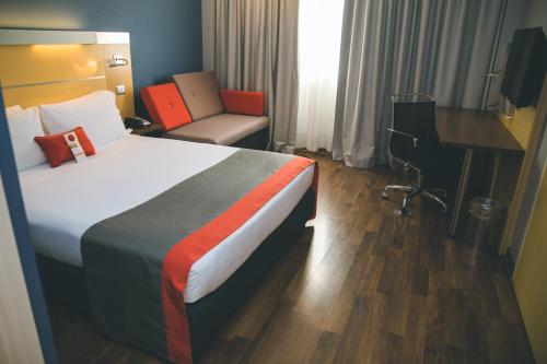 a hotel room with a bed with a desk and a chair at Holiday Inn Express Milan-Malpensa Airport by IHG in Case Nuove