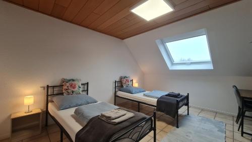 a bedroom with two beds and a table and a window at Gästehaus Zimmer #4 Jülich in Jülich