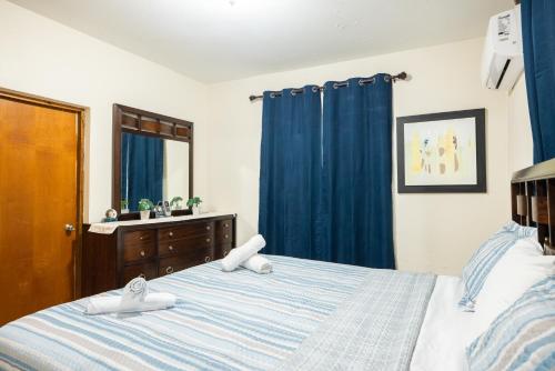 a bedroom with a bed with blue curtains and a mirror at Arenales Guest House in Isabela