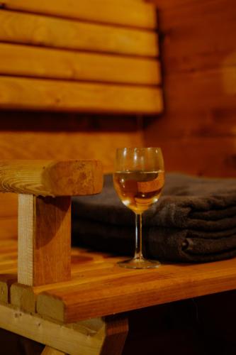 a glass of wine sitting on a wooden table at Osada pod Gwiazdami & SPA - FAMILY ogrodzony dom, prywatne JACUZZI, kominek, grill, ognisko, Kajaki, Plaża, Jeziora in Łasko