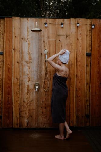 a woman with a towel on her head standing next to a wooden fence at Osada pod Gwiazdami & SPA - FAMILY ogrodzony dom, prywatne JACUZZI, kominek, grill, ognisko, Kajaki, Plaża, Jeziora in Łasko
