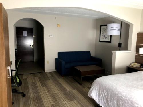 a hotel room with a bed and a blue couch at Holiday Inn Express & Suites Kings Mountain - Shelby Area by IHG in Kings Mountain